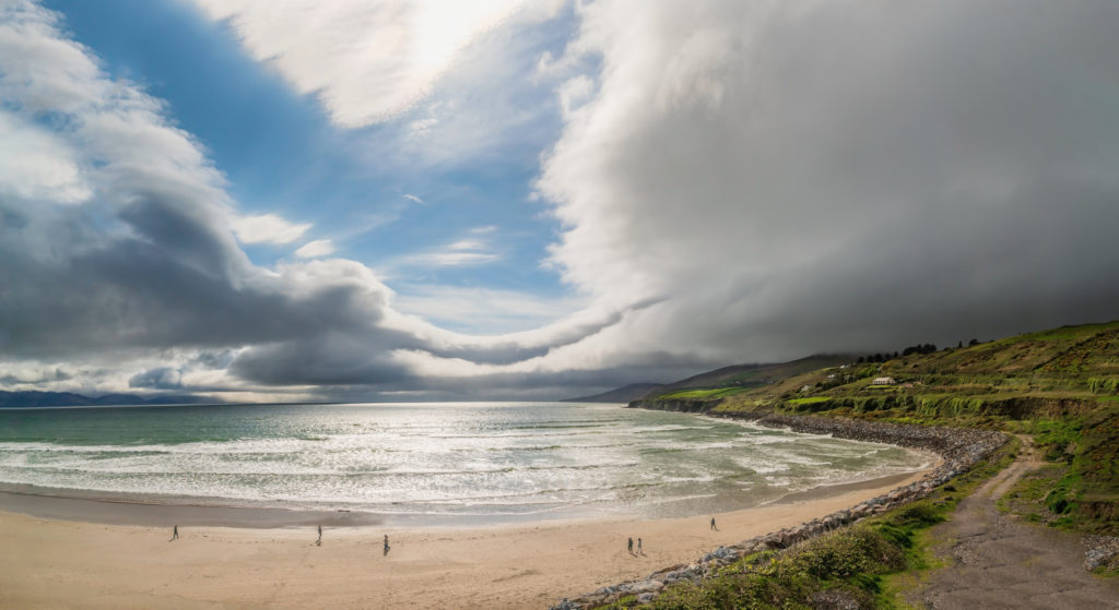 Stunning Coastal Beach View Scenic beach with rolling waves, lush green hills, and dramatic clouds, perfect for seaside relaxation and nature walks.
